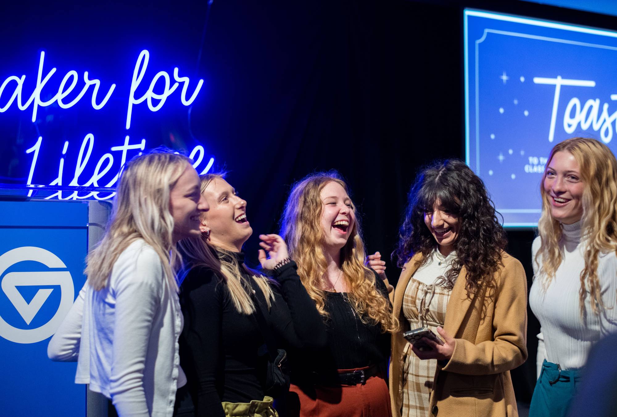 Eight graduates pose for a photo at a Toast event